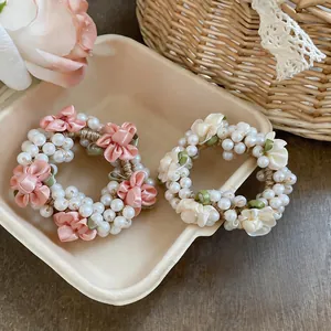 Close-up of elegant pearl hair ties with handmade satin flowers in pink and cream colors