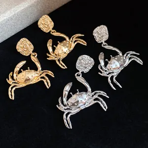 Detailed macro shot of stylish crab-shaped drop earrings in gold and silver metal finishes