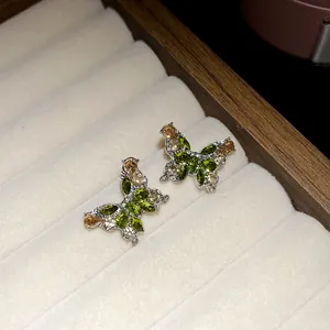 Détail macro de boucles d'oreilles papillon exquises avec cristaux verts et ambrés
