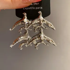 Detailed view of vintage geometric silver earrings with pearls and shiny rhinestones.