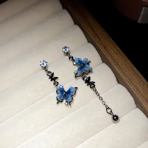 Vue détaillée de boucles d'oreilles papillon asymétriques en résine bleue et zircon