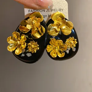 Detailed close-up of vintage style black resin stud earrings with golden metallic flowers