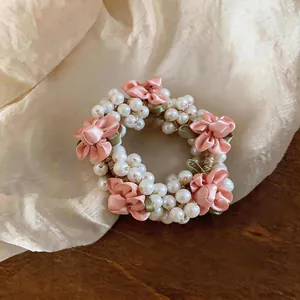 Close-up detail of a sweet pearl and pink fabric flower hair scrunchie accessory