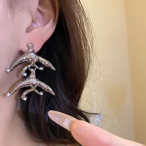 Close-up of retro silver geometric drop earrings with pearls and rhinestones on model's ear.