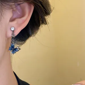 Gros plan de boucles d'oreilles papillon en résine bleue avec zircon scintillant