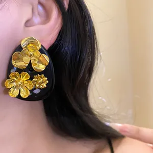Vintage black resin ear studs with golden metallic flowers for a sophisticated look.