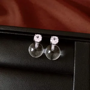Detail of silver stud earrings with square zircon and clear glass sphere drops