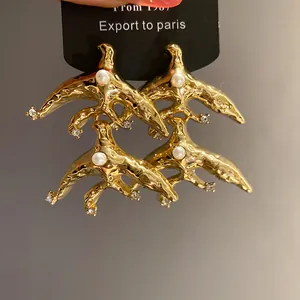 Detailed macro shot of vintage gold bird earrings with pearls and crystal accents