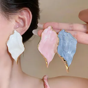 Macro view of textured leaf-shaped oversized stud earrings in white, pink and blue