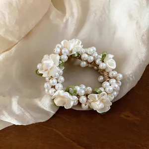 Close-up detail showing the exquisite pearl and cream satin flower hair tie on silk fabric