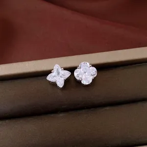 Detailed close-up of asymmetric clover flower studs set with brilliant clear zircons