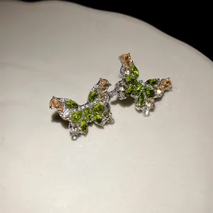 Vue macro détaillée de boucles d'oreilles papillon en argent avec zircons verts