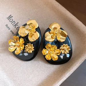 Close-up of vintage black resin stud earrings with golden flower ornaments
