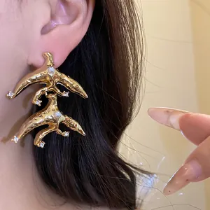 Close-up view of vintage gold bird drop earrings with pearls and sparkling crystals