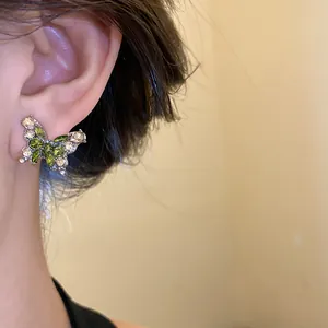 Vue détaillée d'une boucle d'oreille papillon avec des zircons verts et clairs.