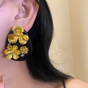 Close-up of vintage resin flower stud earrings with golden floral accents.