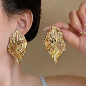 Detailed view of oversized gold earrings with unique irregular hammered metal texture