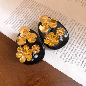 Macro detail of vintage gold floral resin stud earrings resting on a book background