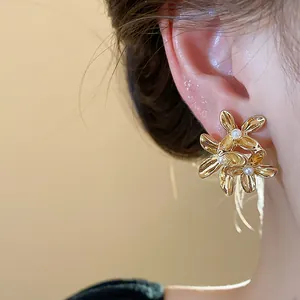 Close-up detail of elegant gold floral earrings featuring white pearls on an ear
