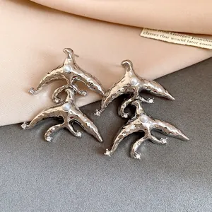 Macro view of unique silver geometric earrings featuring pearl and sparkling crystal details.