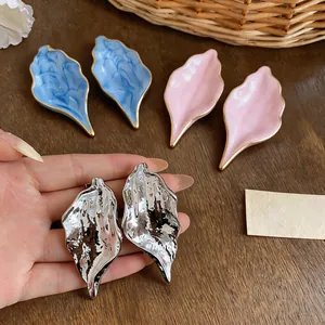 Detailed macro view of silver textured leaf statement earrings with pink and blue pairs