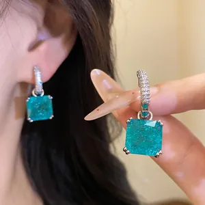 Primo piano di eleganti orecchini pendenti in zircone quadrato blu con cerchi argento