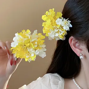 Close-up of elegant yellow and white fabric flower hair clips for a sweet resort look