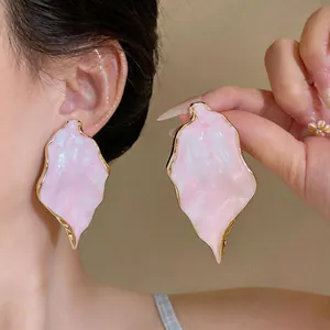 Detailed close-up of large irregular pink marble texture earrings with elegant gold trim