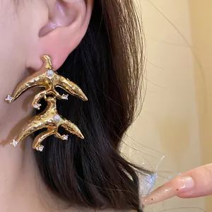Detail of gold swallow-shaped earrings with pearls and crystals on ear