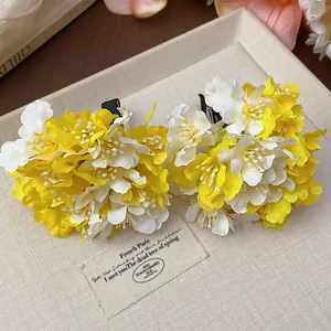 Detail view of yellow and white fabric flower hair clips on a decorative beige tray
