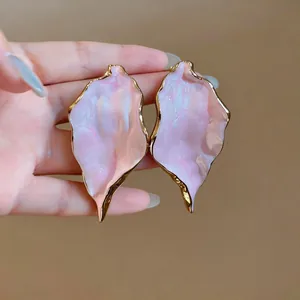 Close-up of pink marbled texture earrings with golden metallic edges in a macro view.