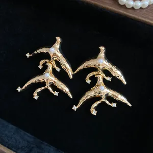 Detailed view of vintage gold hammered bird earrings with pearls and rhinestones