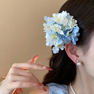 Close-up of elegant blue and white fabric flower hair clip worn on long wavy hair.