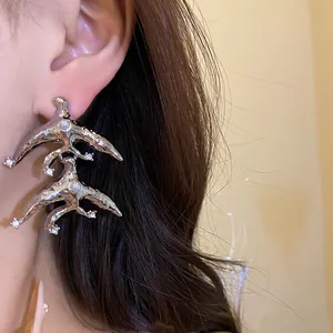 Close-up shot of a silver geometric earring with pearl and rhinestones on an ear.