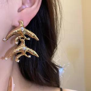 Close-up of luxury vintage gold swallow drop earrings with inlaid pearls and crystals