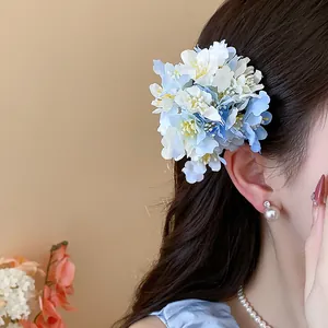 Close-up of sweet fabric flower hair clip in blue and white on wavy brown hair
