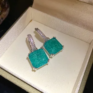 Dettaglio di orecchini a sospensione quadrati vintage turchesi con cerchi in zirconi