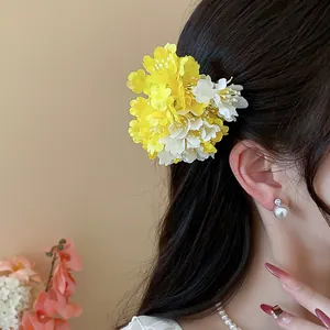 Floral fabric hair clip in yellow and white, styled on long black hair for a vacation look