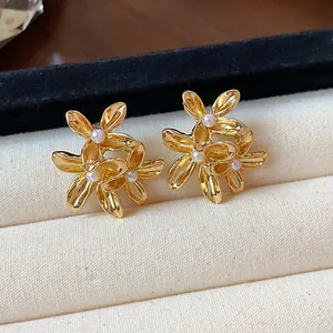 Macro detail of elegant gold floral stud earrings featuring delicate pearl centers