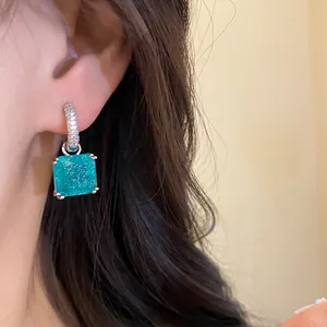 Primo piano di orecchini a cerchio in argento con zircone quadrato turchese