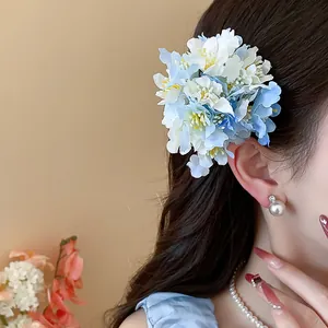 Detailed view of sweet blue and white fabric flower hair clip worn on wavy brown hair