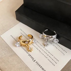 Close-up detail of elegant gold and silver star pendant ear cuffs with sparkling zircon