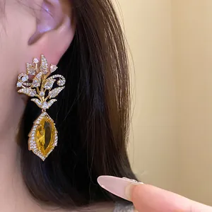 Detailansicht eleganter 18k vergoldeter Blumen-Ohrhänger mit gelbem Edelstein.