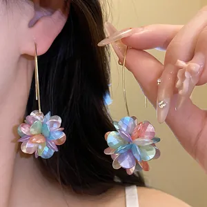 Detail view of colorful pearlescent flower ball drop earrings with golden hooks