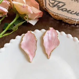 Close-up of pink marble-textured earrings with elegant gold metal trim.
