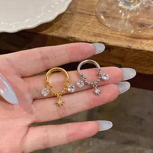 Close-up of star and zircon charm ear cuffs in gold and silver finish.
