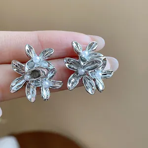 Detailed view of elegant silver-toned floral stud earrings with tiny pearl accents