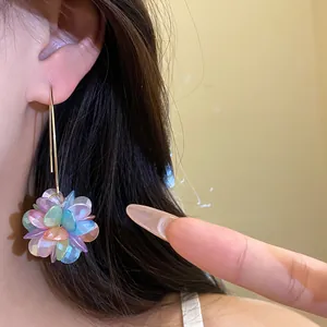 Close-up of sweet colorful iridescent petal flower ball pendant earrings on ear.