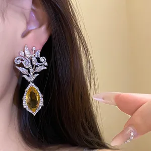 Detailaufnahme der luxuriösen, 18 Karat vergoldeten Zirkon-Blumenohrringe mit gelbem Anhänger