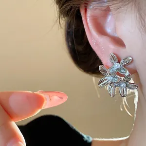 Close-up of elegant silver flower earrings featuring delicate white pearls on a model.